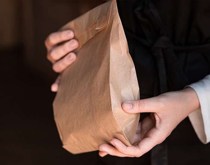 Χέρι κρατά χάρτινη σακούλα kraft